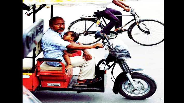 man drive e rickshaw with baby in lap